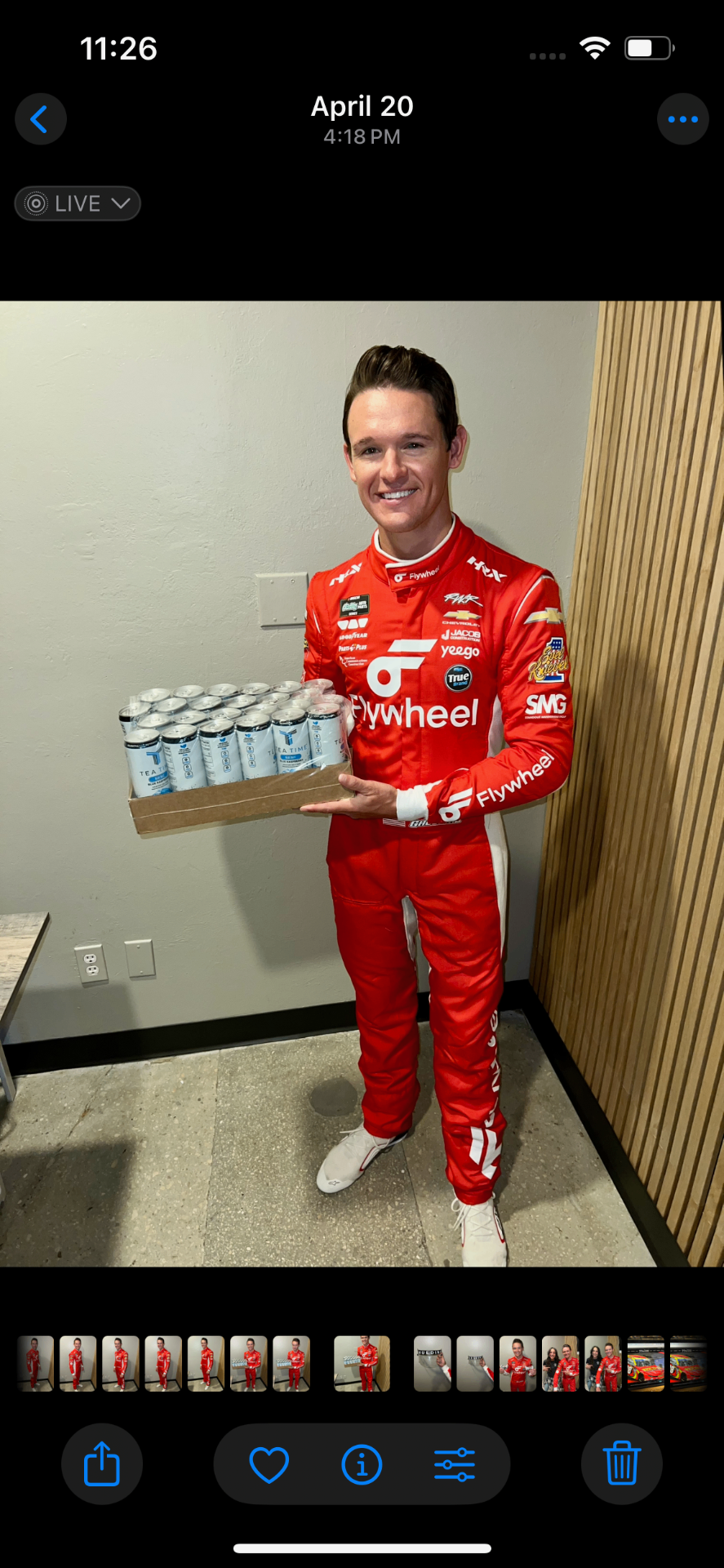 Gray Gaulding in a red racing suit carrying a case of Tea Time drinks.